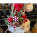 This shows the Christmas arrangement on the elf hat. It includes pine sprigs, a reindeer ornament, red berries, and a faux peppermint candy.